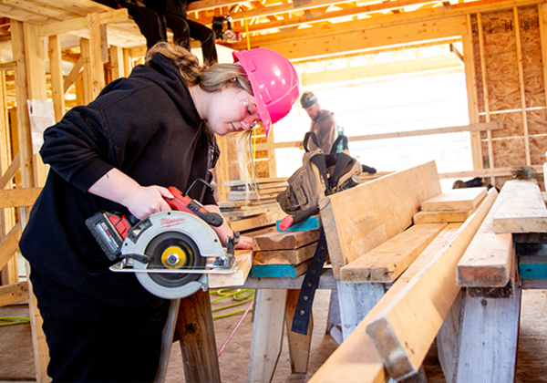 Carpentry student cutting a piece of wood