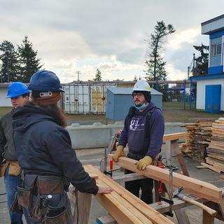 Three carpentry students working at sawhorses