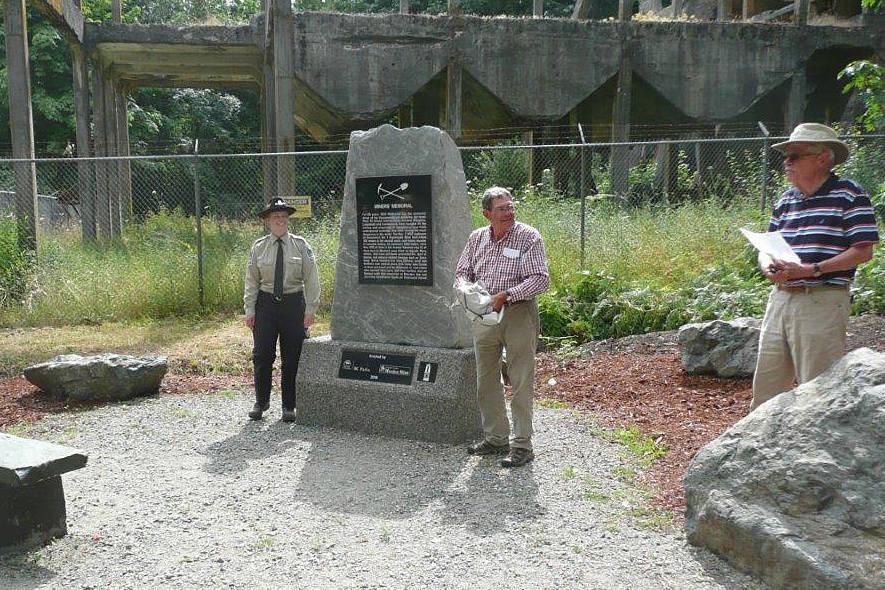 People standing by a cement monument in a garden setting.