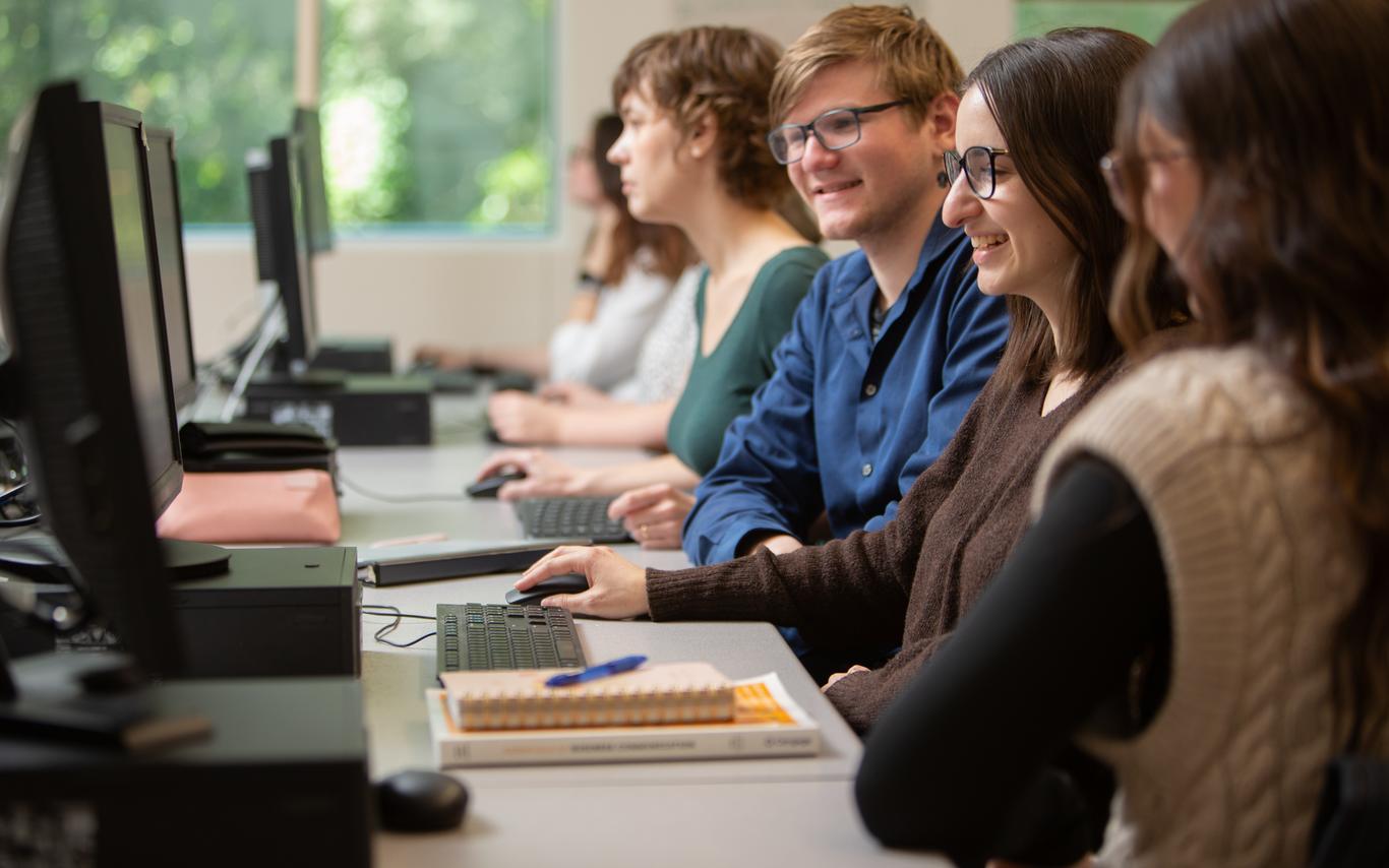 Two female and one male Office administration students work together around a computer